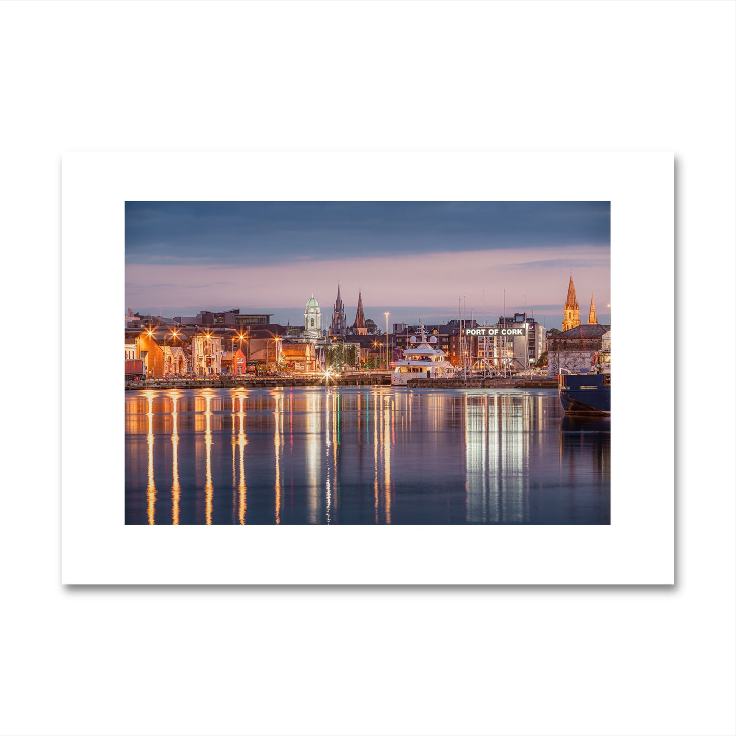 Print in colour of fine art photograph of Cork, Ireland. The photo captures a serene waterfront view with reflections of historic buildings and church spires in the water. Limited Edition print