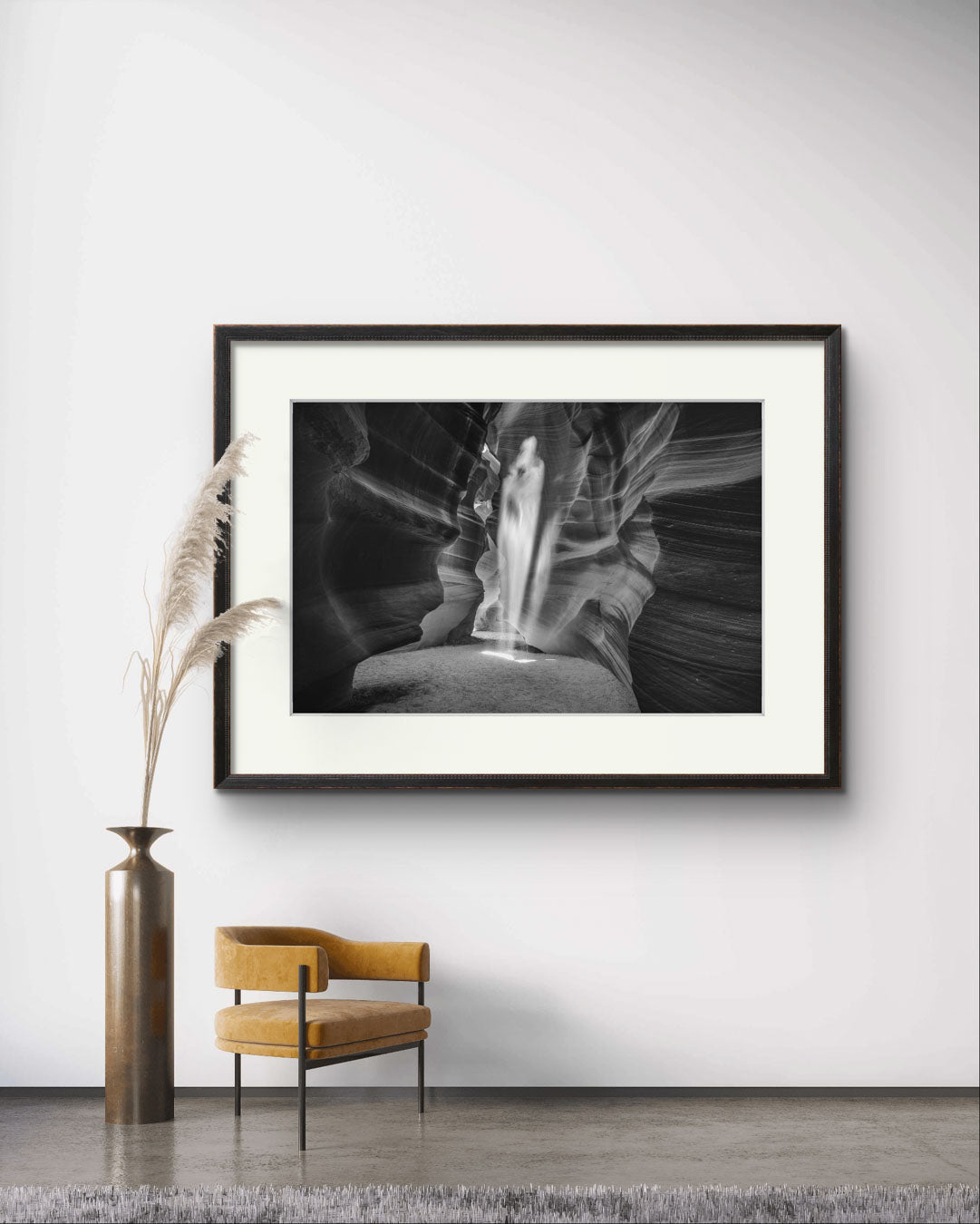 a waiting hall with a chair and stylish large vase . on the wall is hung up black and white photograph of a canyon passage with sand threw in the air in a shape of a ghost. Antelope Canyon. Navajo. Page. Arizona