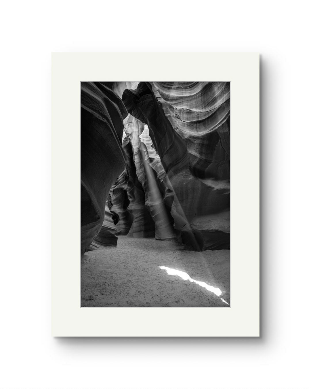 Unframed Fine Art black and white photograph of Canyon’s narrow passageway with the light cascading down the walls like a waterfall of illumination. The intricate
patterns of the sandstone, carved by centuries of wind and water, create a mesmerizing texture that draws the eye upward. Antelope Canyon, USA, Arizona