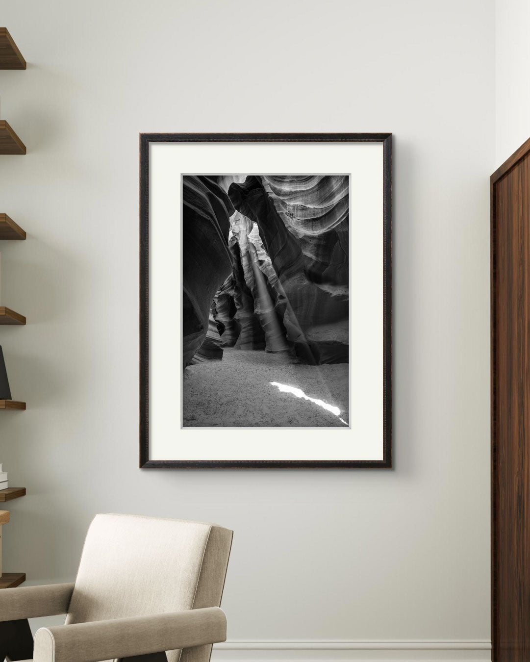 A small office space and on the wall is Framed Fine Art black and white photograph of Canyon’s narrow passageway with the light cascading down the walls like a waterfall of illumination. The intricate patterns of the sandstone, carved by centuries of wind and water, create a mesmerizing texture that draws the eye upward. Antelope Canyon, USA, Arizona.