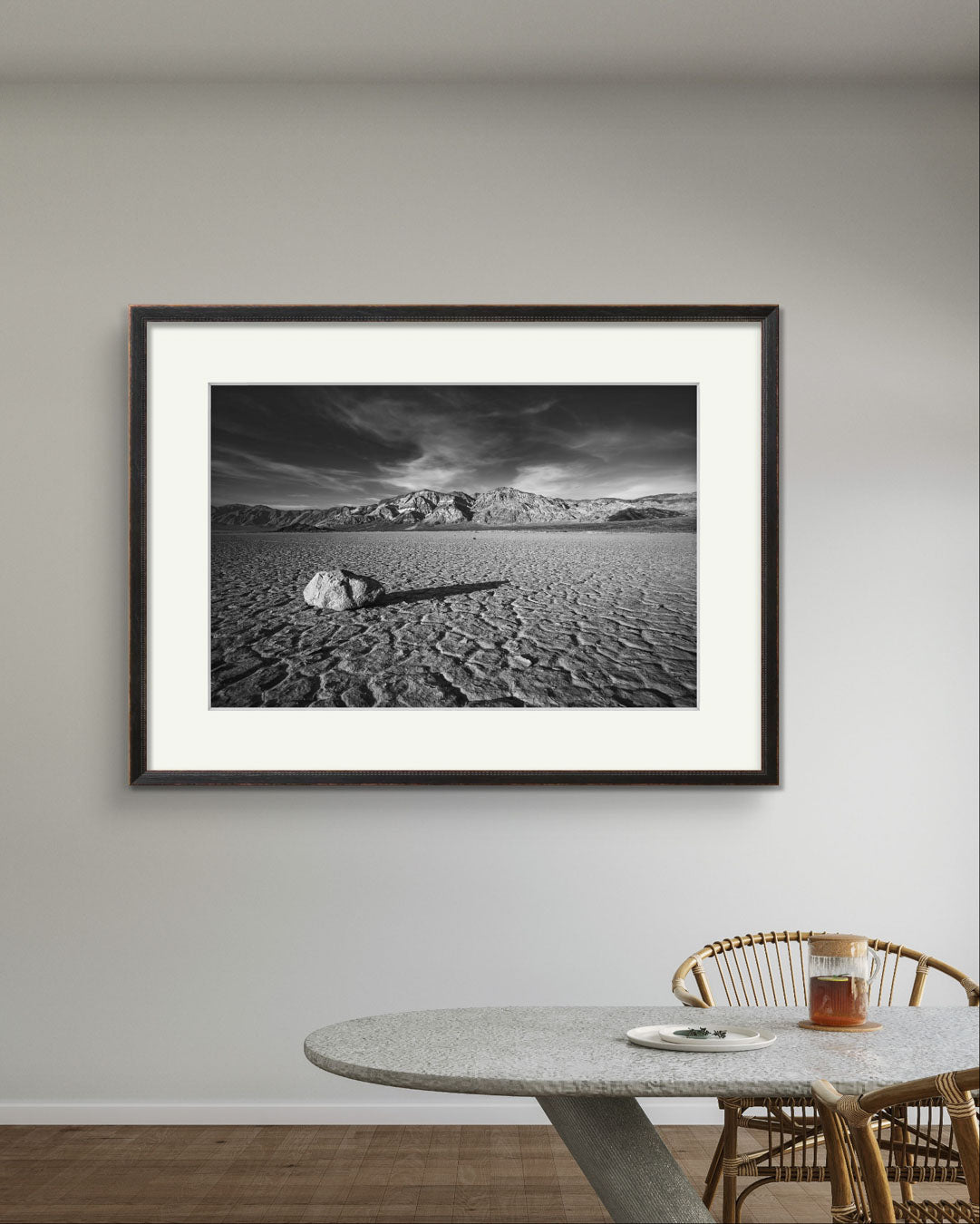A desert valley in Eastern California. Black and white fine art framed photograph print of a striking desert landscape in Death Valley National Park. Featuring a solitary rock on the cracked, dry lakebed of the Racetrack Playa, mountain ranges in the background. Perfect for home decor, wall art, unique nature and landscape prints, this image captures the stark beauty, texture, and timeless appeal of the American Southwest.