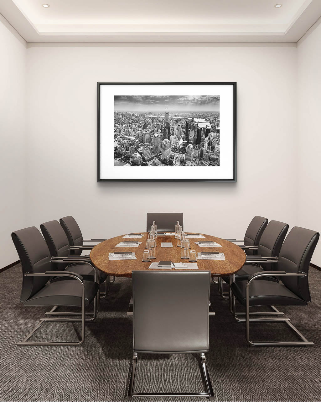 Meeting room in the office. wooden chair in the middle with six chairs an over on the wall is Black and white photograph of skyscrapers an buildings of New York City. Helicopter View. Focal point is One World Trade Center.