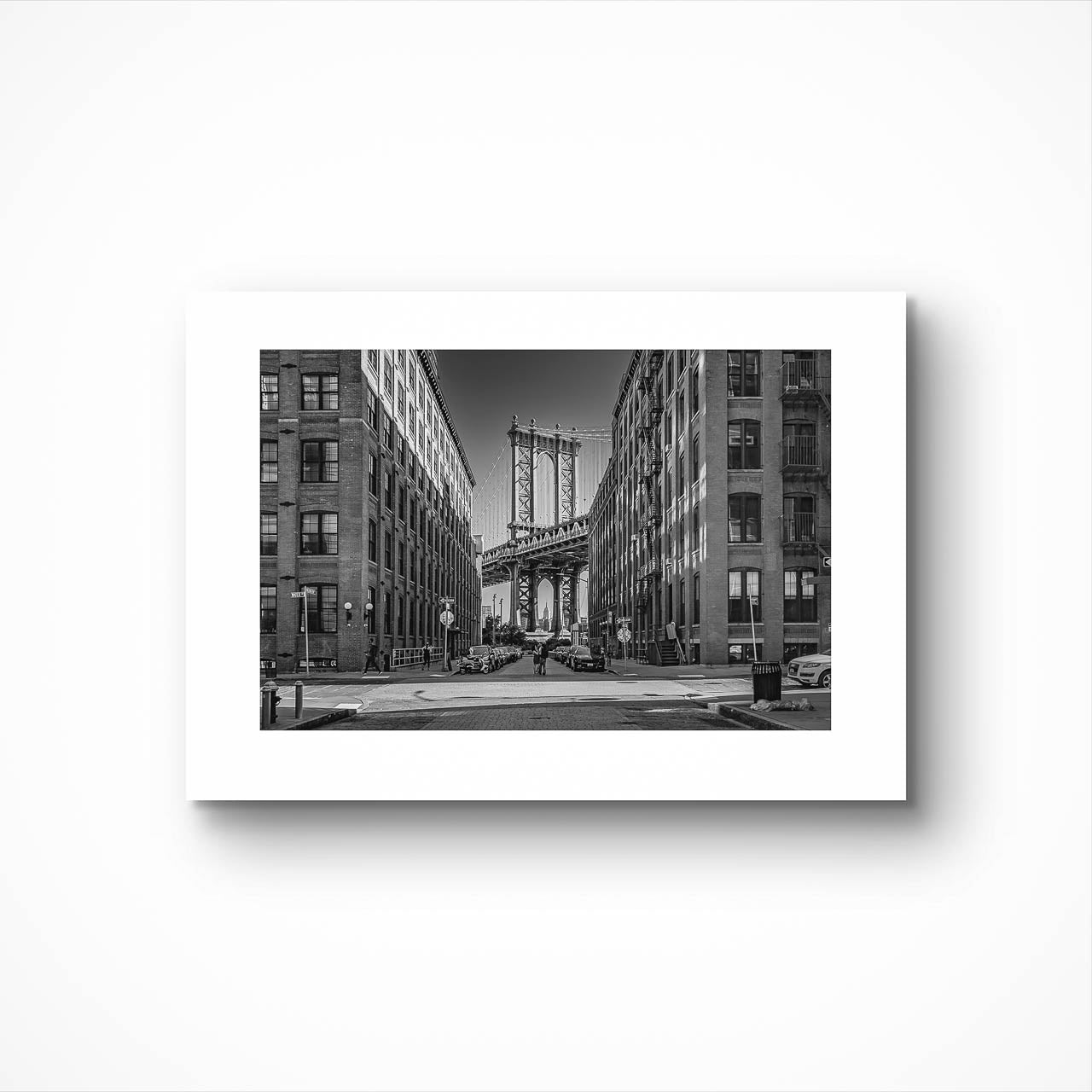 Unfamed black and white photograph of Manhattan Bridge in between buildings. NYC. New York City.