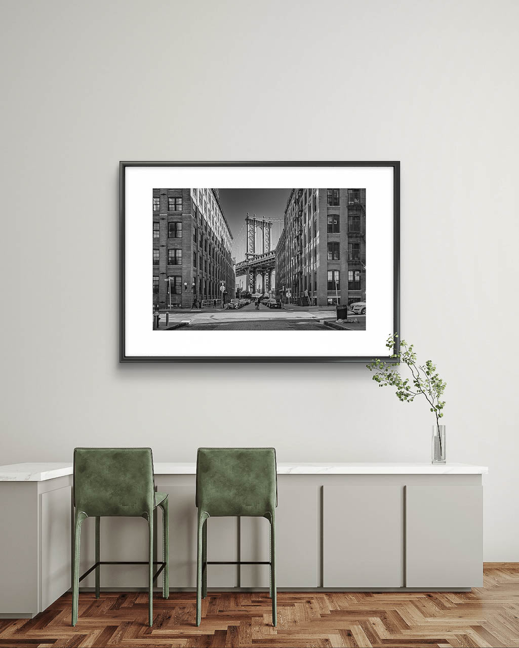 Minimalistic table an two chairs by it. On the wall is hung Framed black and white photograph of Manhattan Bridge in between buildings. NYC. New York City.