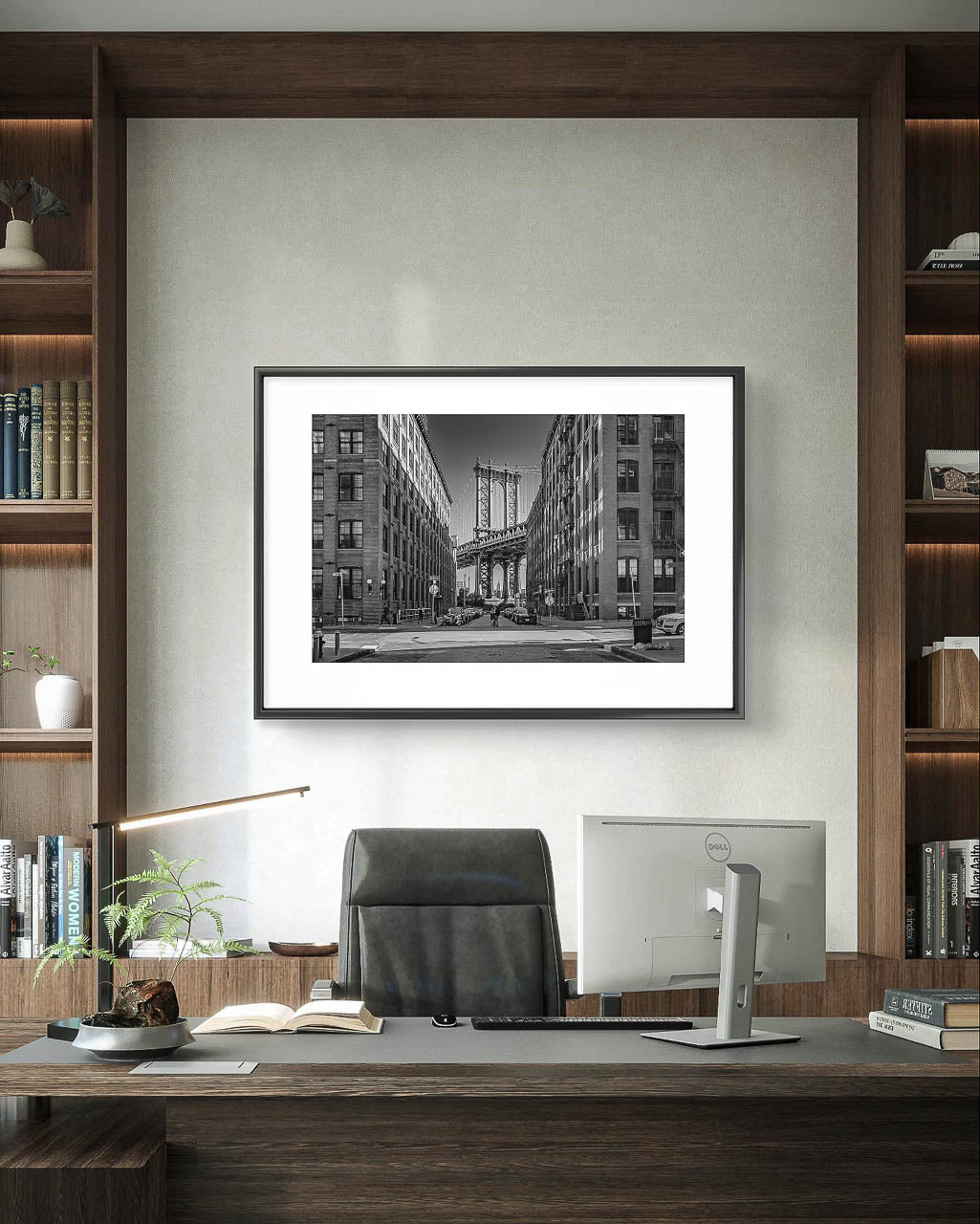 The desk of a manager or CEO, behind it is hung a Framed black and white photograph of Manhattan Bridge in between buildings. NYC. New York City.