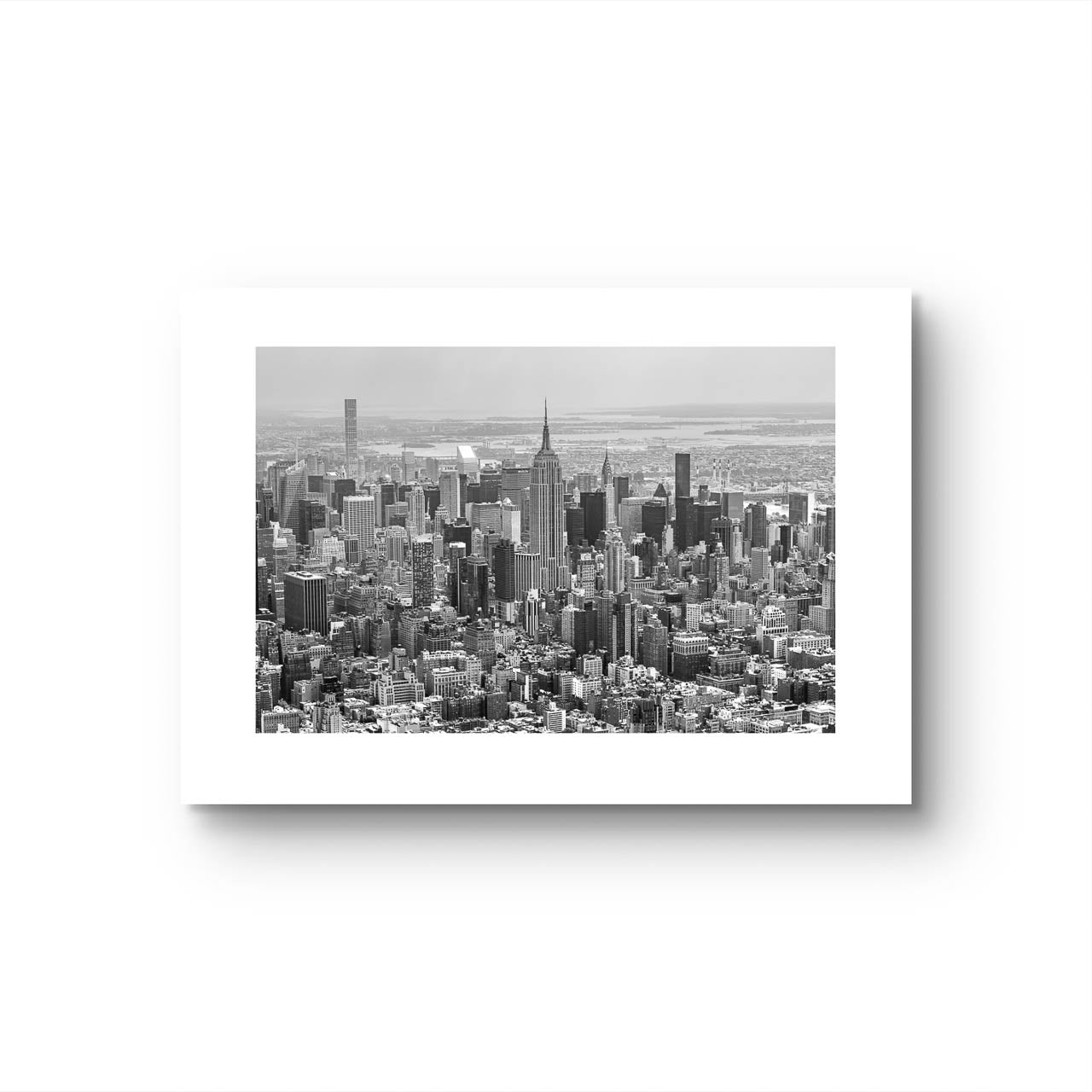 Not framed black and white fine art photography print. Aerial view of Manhattan with the iconic Empire State Building reigning supreme at its center. The photograph captures the city in all its grandeur, with skyscrapers reaching for the sky and the bustling streets below. NYC. New York City