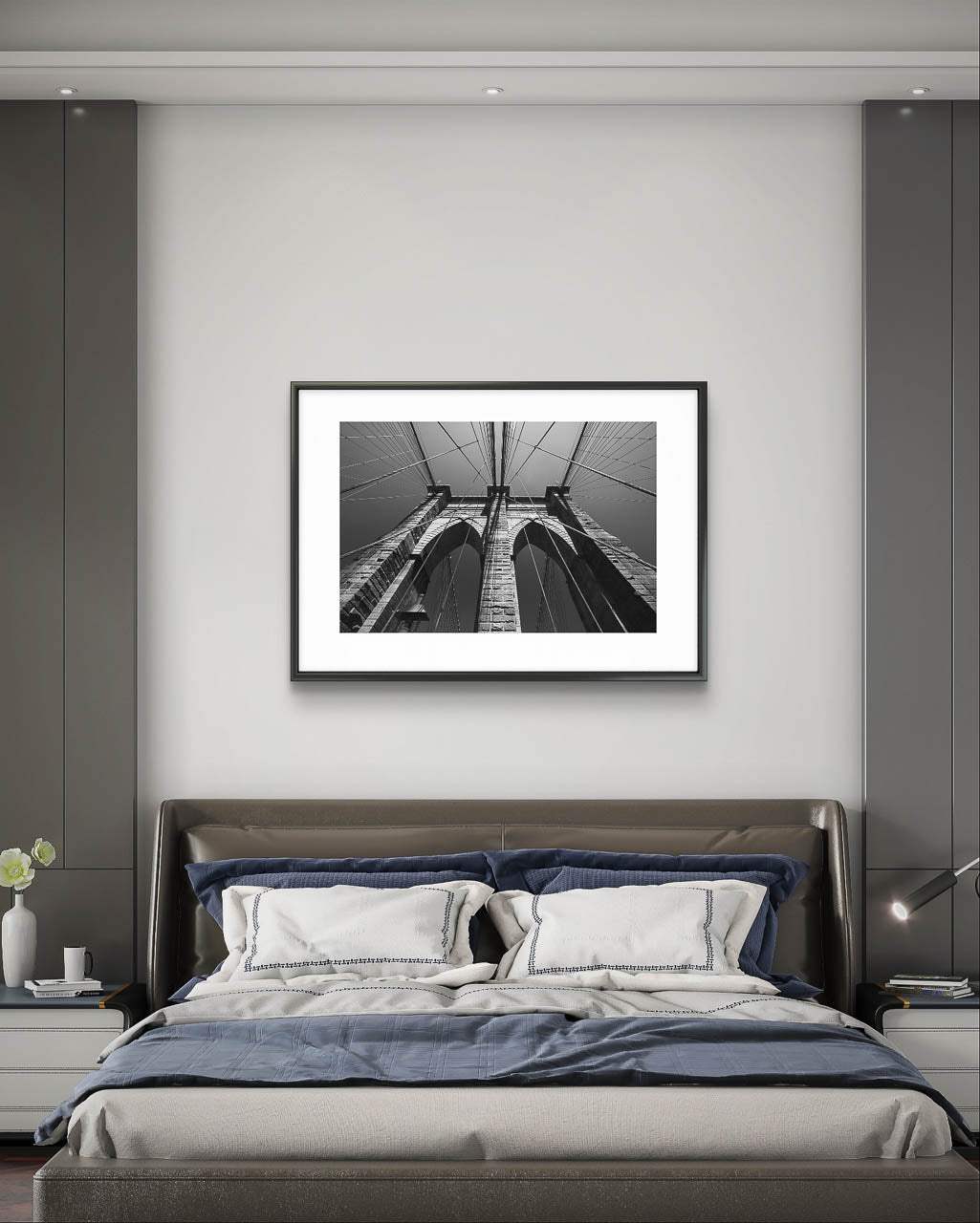 Bedromm in teh hotel room. over large bed is hanging framed photograph of Brooklyn Bridge, fine art black and white print. Shot from the perspective of a pedestrian looking up, the image highlights the intricate Neogothic arches of one of the bridge's towers. Fine art photography print. Limited Edition, NYC, New York City, USA