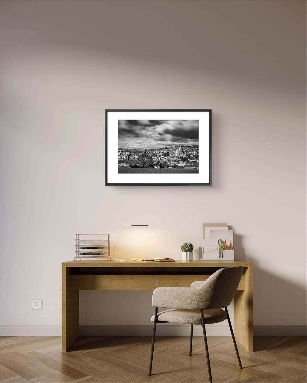 Grey Wall, Framed Black and white photograph of a cityscape with a cloudy sky, capturing a wide view of buildings and distant hills in the background. The buildings appear detailed, with a mix of architectural styles, creating a sense of depth and texture in the urban landscape. Picture is hanged over an office desk with a desk lamp and comfy chair. Cork City, Ireland, Young Offenders Movie Iconic View. Bells Field. Shandon Bell's. Fine Art print, Limited Edition