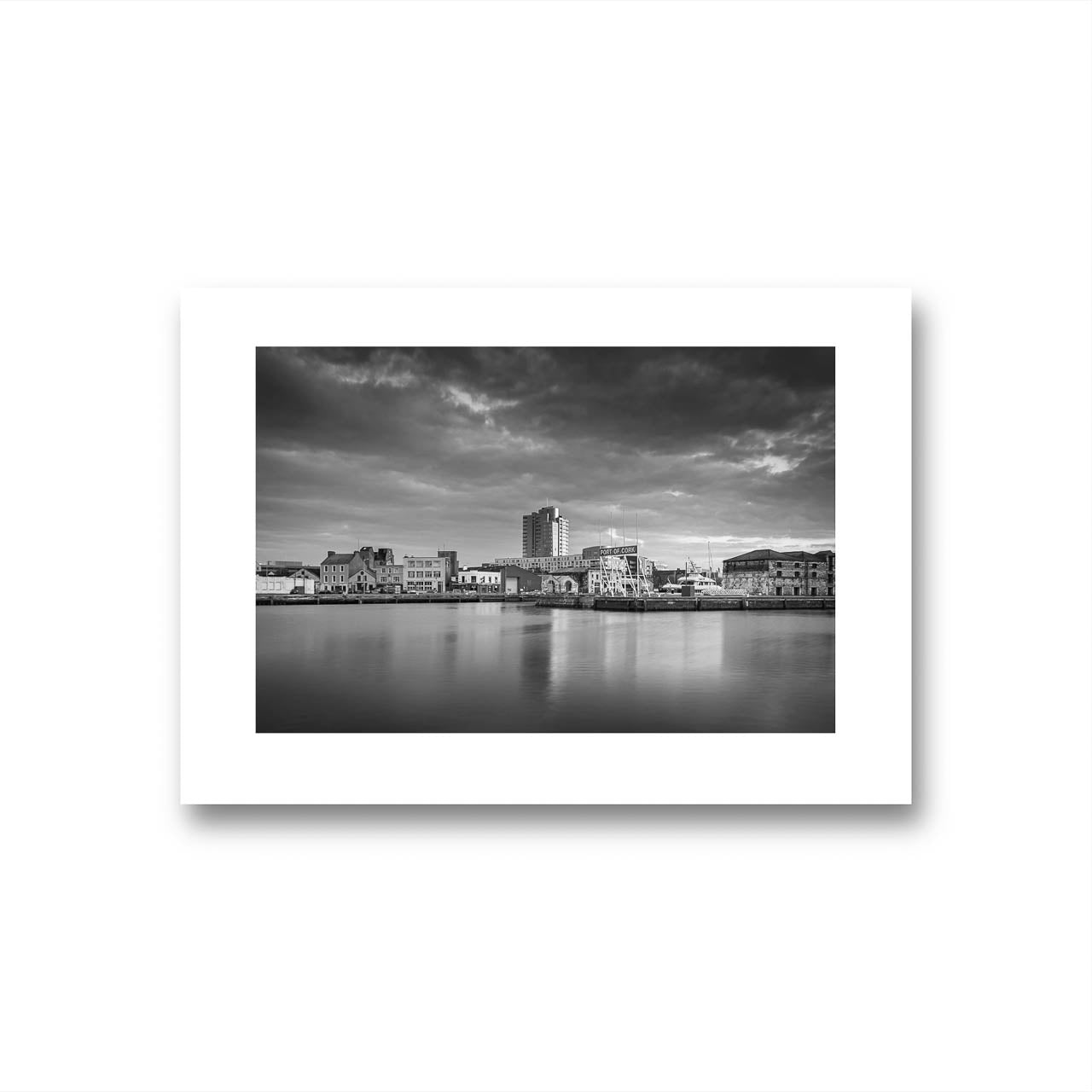 Black and white Fine Art 
photograph of a calm waterfront scene with industrial buildings in the focal point. The long exposure effect creates smooth water reflections. streaked clouds in the sky, enhancing the tranquil, moody atmosphere of the port area .Albert Quay & Victoria Rd.  Limited Edition Print, Fine Art photography, Cork City, Ireland