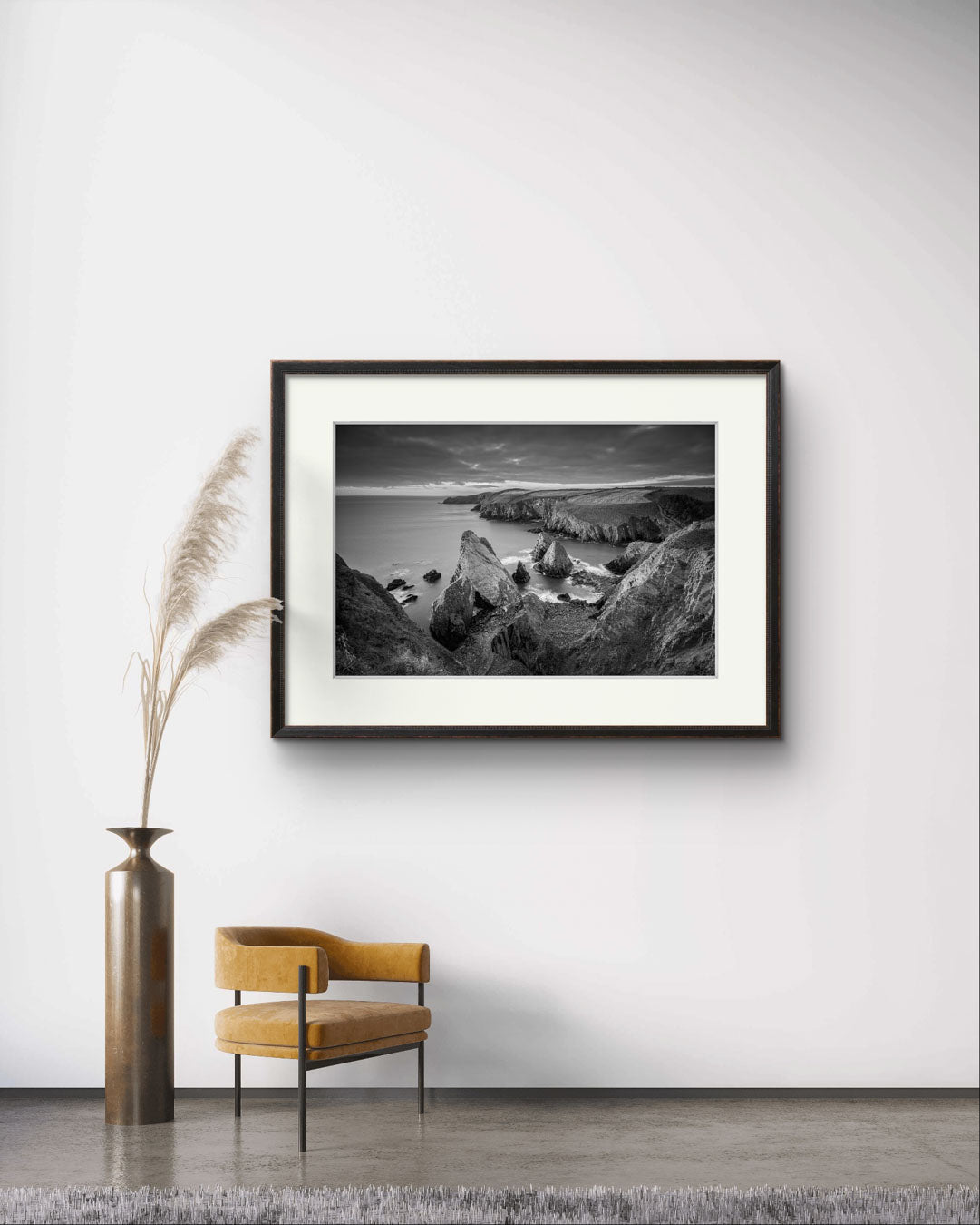 waiting ares with chair and large vase. on the wall is Framed black and white photograph of coastal landscape. Cork Ireland