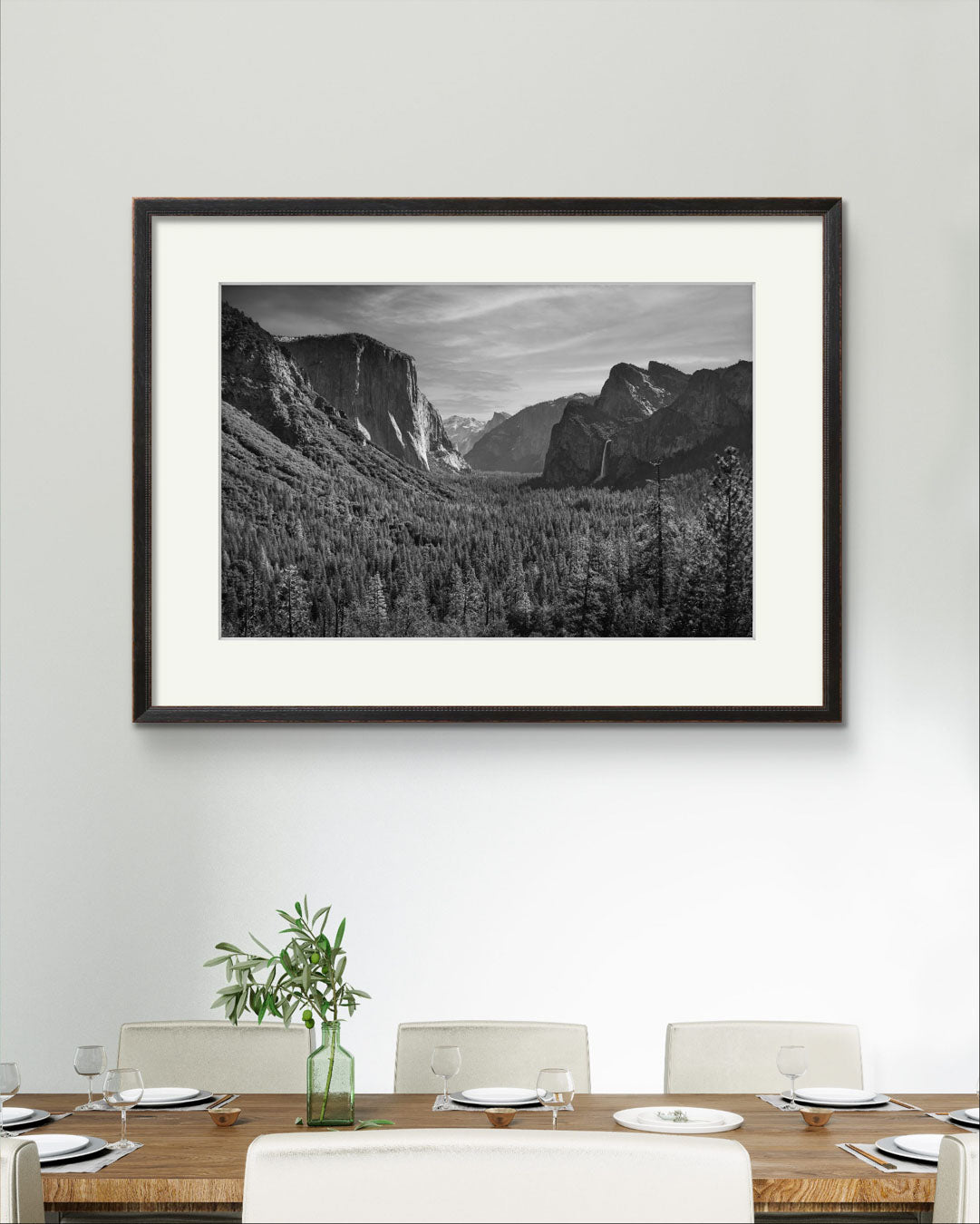 A luxury dining table and in the background wall art. Framed fine art photography print of the Yosemite Valley. Made famous by Ansel Adams. Valley View. California. USA