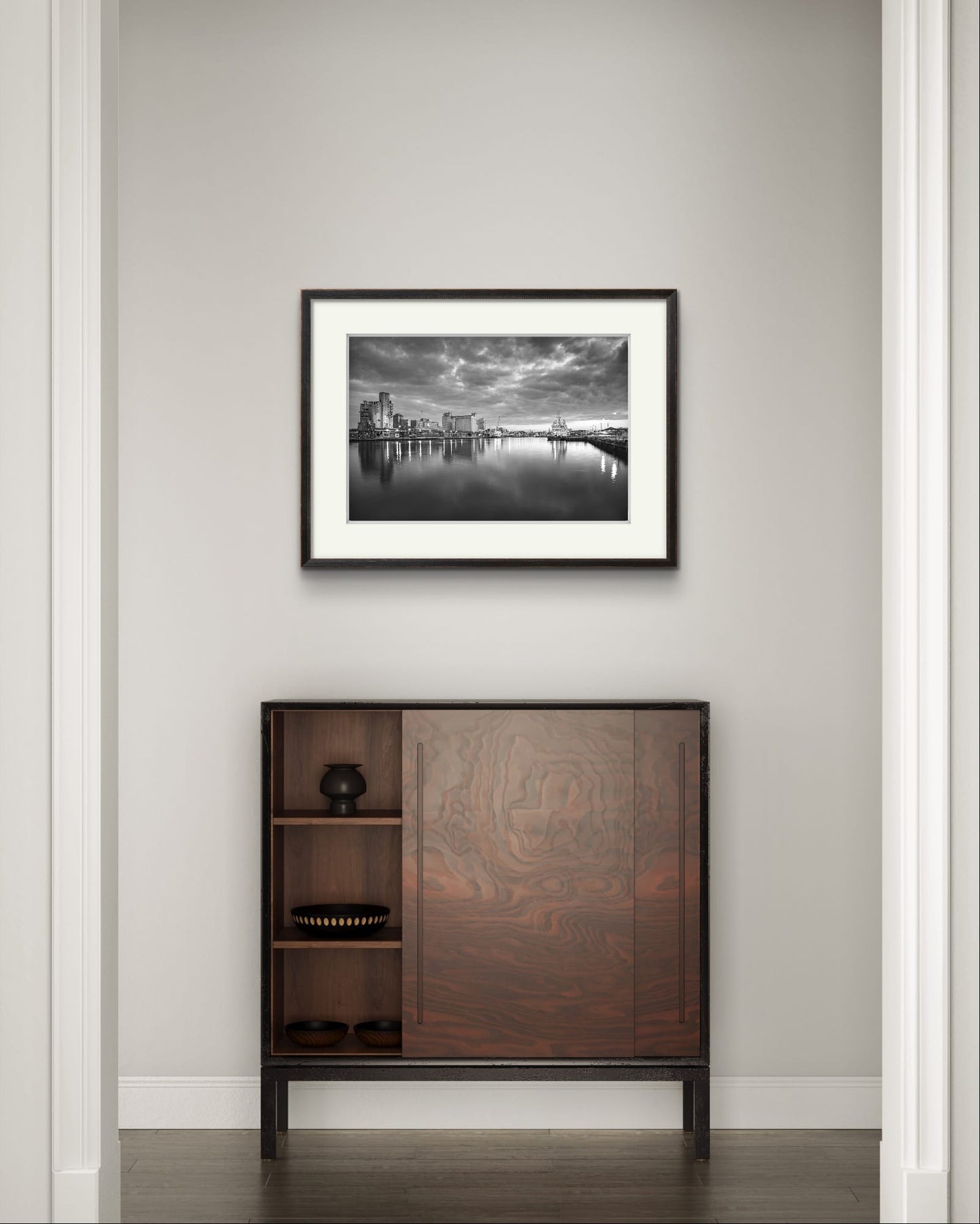 Mahogany console table and Black and white Fine Art Photography Print. The calm river reflects lights from buildings along the shoreline, creating a shimmering effect on the water. A cloudy sky adding a serene, moody atmosphere. The industrial buildings lights contrast with the darkening sky. Kennedy Quay, Port of Cork, Limited Edition Print, RH Hall, Cork City, Ireland