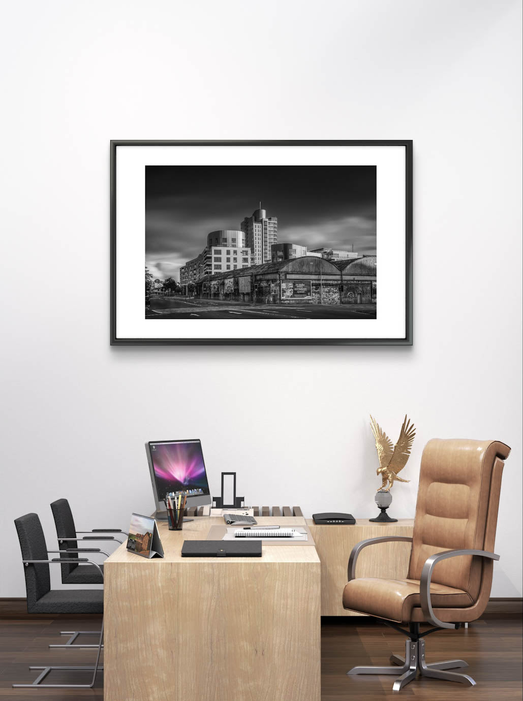 CEO office, on the wall framed Black and white photograph of an urban street corner with a row of old, weathered warehouses in the foreground. The warehouses are covered with vintage posters and graffiti. In the background, modern high-rise buildings stand against a dramatic, cloudy sky, contrasting the historic architecture in the foreground. The photo has a moody, timeless atmosphere. Cork City, Ireland. Fine Art Photography. Limited Edition.
