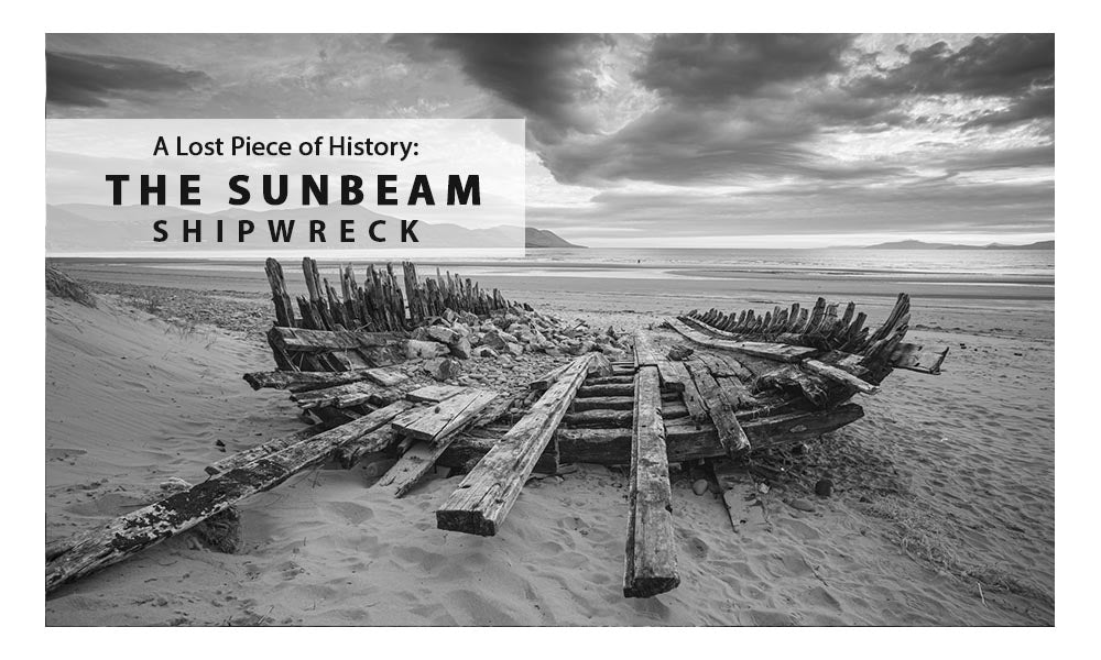 Black and white photograph of the Sunbeam Shipwreck on a sandy beach in County Kerry, Ireland, under dramatic skies