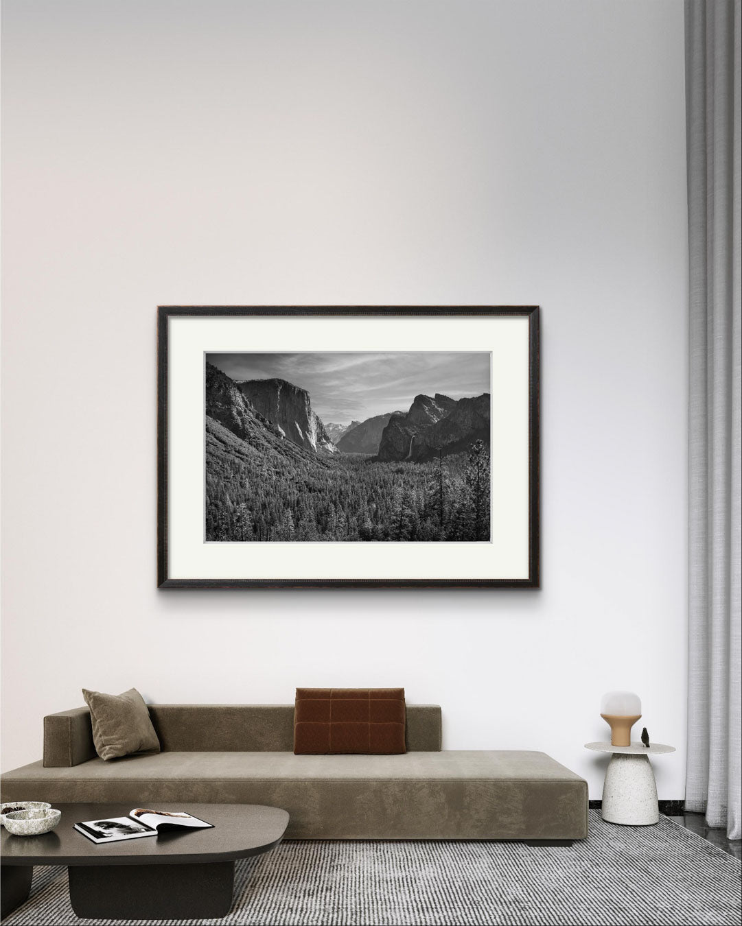 Nice large sofa and many elements of home decor. Also on the wall is framed fine art photography print of the Yosemite Valley. Made famous by Ansel Adams. Valley View. California. USA