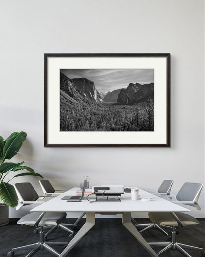 a conference room with table, chairs, laptop and projector. on the wall is large size Wall art. Framed fine art photography print of the Yosemite Valley. Made famous by Ansel Adams. Valley View. California. USA