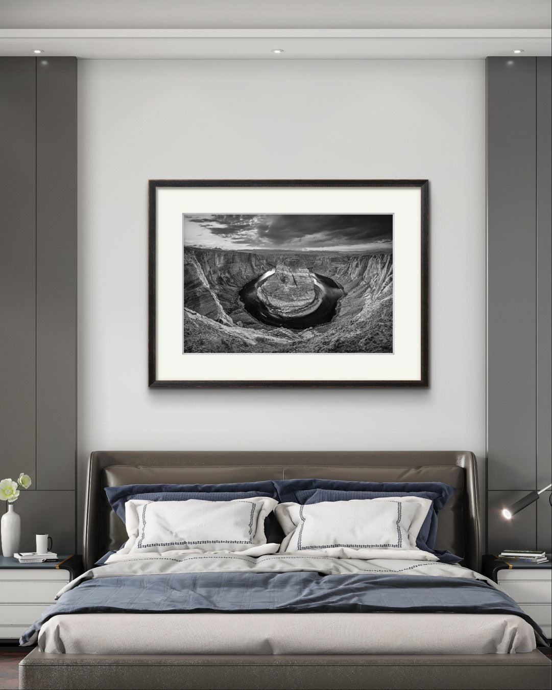 a hotel room with large bed. Above is hanging large wall art. Black and white fine art photography print of a horseshoe-shaped incised meander of the Colorado River, Page, Arizona. USA