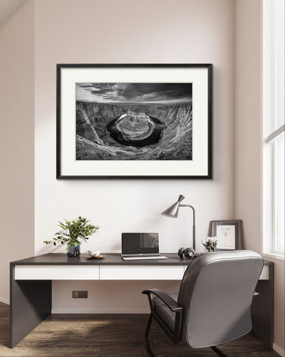 very bright office. on the wall you can see large piece of home decor wall art. Framed, Black and white fine art photography print of a horseshoe-shaped incised meander of the Colorado River, Page, Arizona. USA