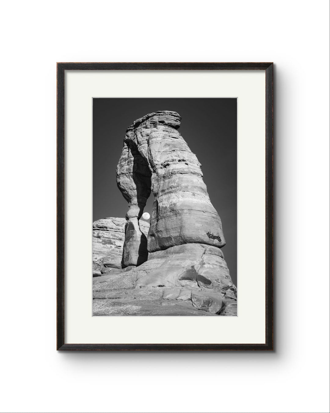 Framed Fine Art black and white photograph of impressive large arch 
 and visible moon through it. Delicate Arch, Moab, USA, Arches National Park