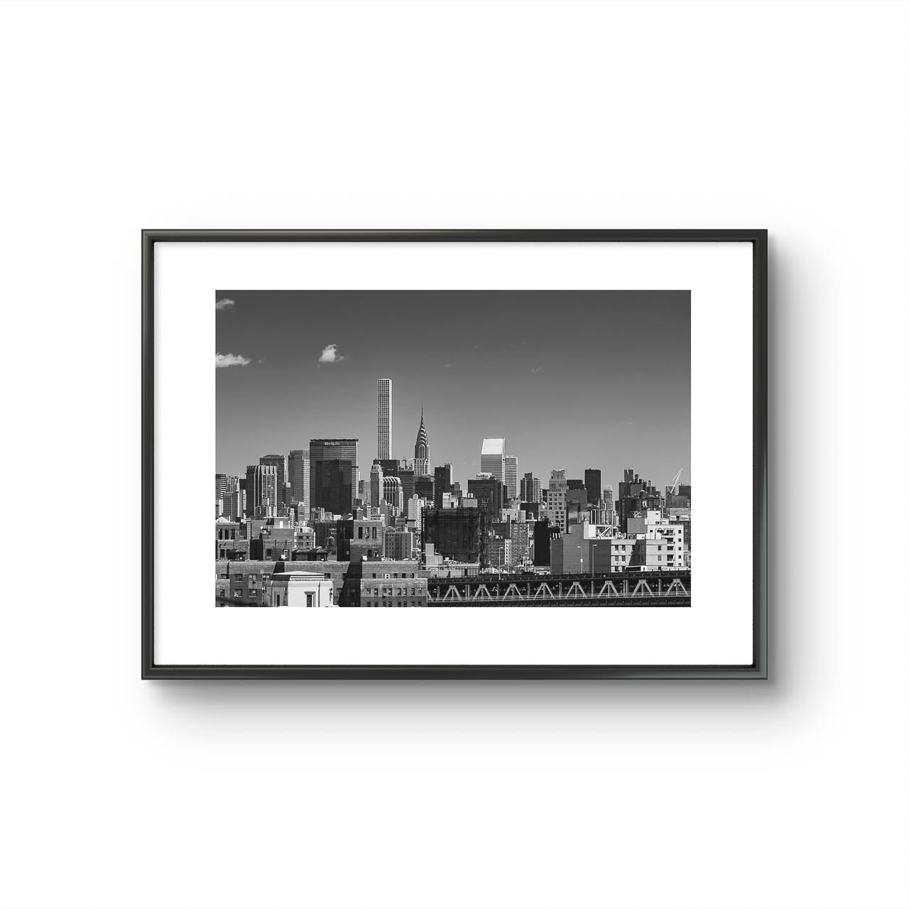 Framed black and white photograph of New York City skyline. All buildings towering behind waterfront. Taken from Brooklyn Bridge side. Manhattan, NYC, USA