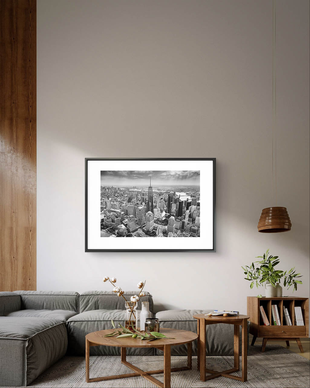 Modern Living room with grey large sofa and wooden coffee table and book shelf . On light grey wall is hanged Black and white photograph of skyscrapers an buildings of New York City. Helicopter View. Focal point is One World Trade Center. 