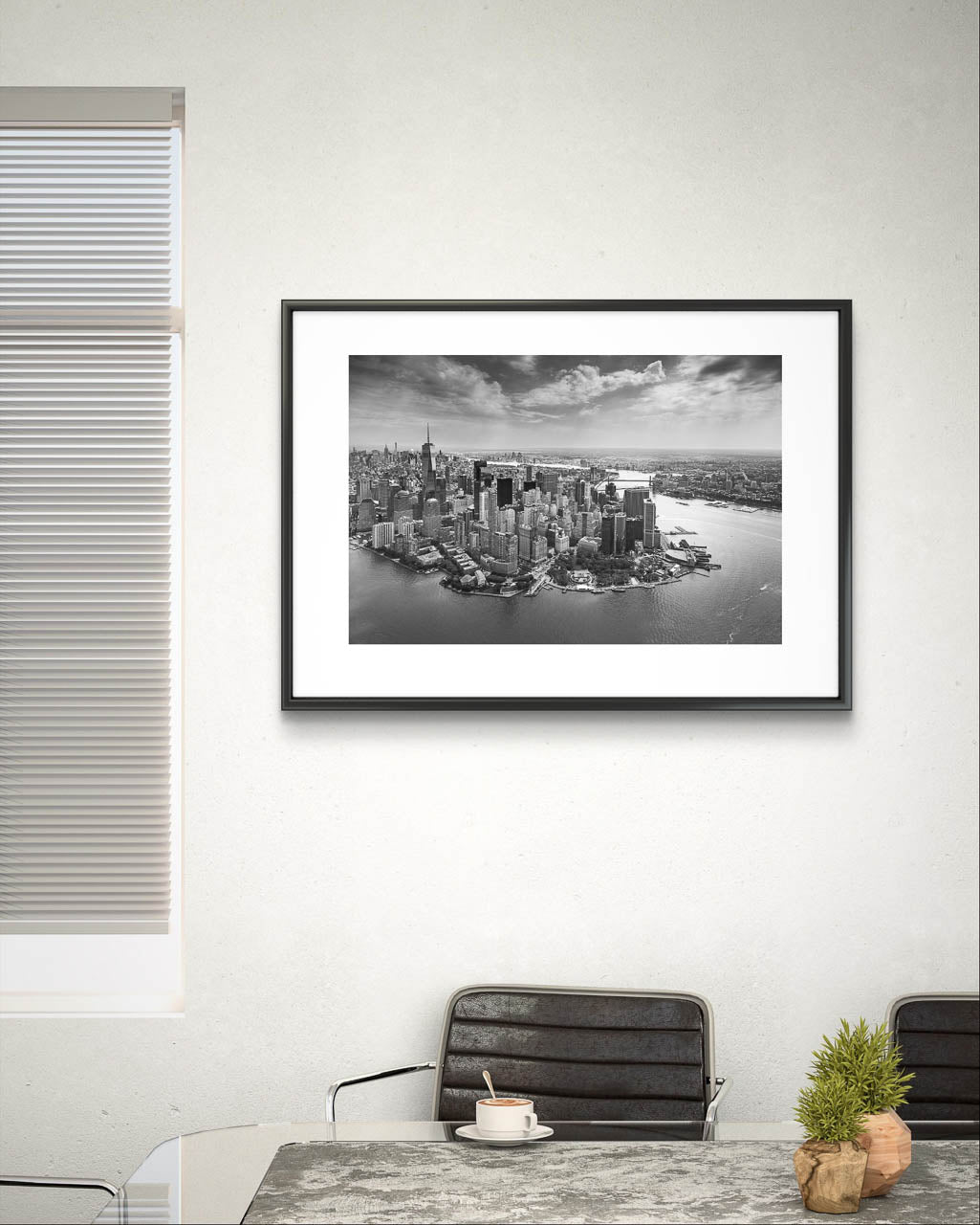 Kitchen table with a cappuccino. On the wall is framed black and white fine art photography Print. Aerial view of Manhattan. Financial District and towering skyscrapers of Wall Street. New York City.