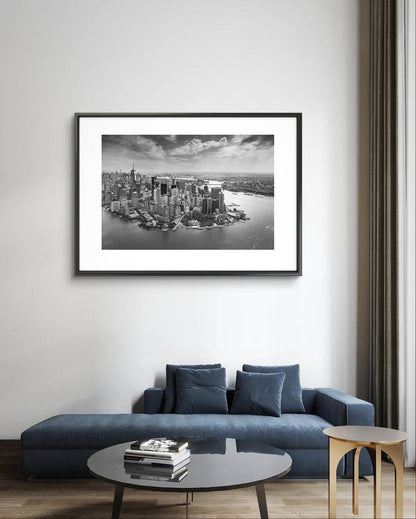 Nice living room, with sofa and small table. On the wall Framed black and white fine art photography Print. Aerial view of Manhattan. Financial District and towering skyscrapers of Wall Street. New York City.