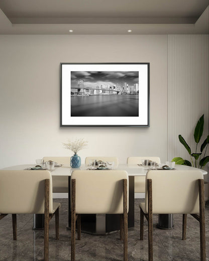 Bright room with modern design. Beige wall with framed black and white photograph of Brooklyn Bridge taken from a distance. Dramatic sky and smooth water. NYC. New York City.