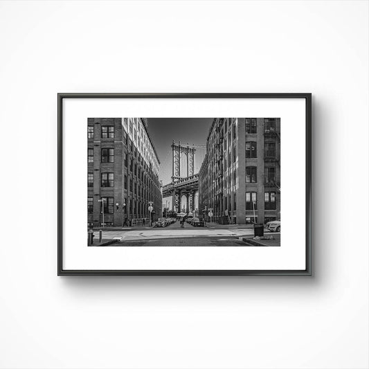 Framed black and white photograph of Manhattan Bridge in between buildings. NYC. New York City.