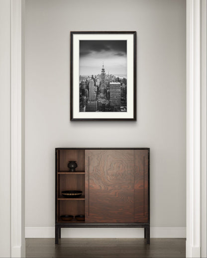 A narrow wall with  displayed Black and white photography print. A breathtaking view of Manhattan from the terrace of the Rockefeller Centre, looking southward, with the majestic Empire State Building commanding the scene as the focal point. New York City.